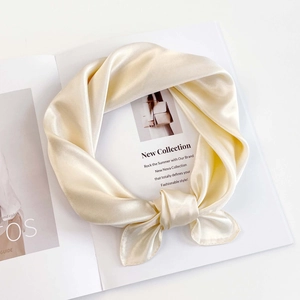 Detailed view of champagne satin silk scarf tied in a knot on minimalist magazine background