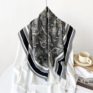 Detailed view of large square silk scarf featuring grey paisley patterns on a white shirt