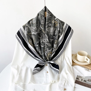 Detail view of gray floral paisley silk scarf tied on a white shirt collar for women