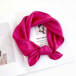 Detail of a magenta silk scarf tied in a bow on a fashion magazine for luxury styling