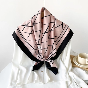 Detail of silk-feel scarf with geometric lines and floral prints on a white shirt