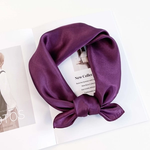 Detail of a deep purple satin scarf tied in a bow with a smooth glossy texture