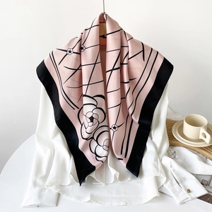 Detailed view of pink silk scarf with black floral camellia print and grid pattern