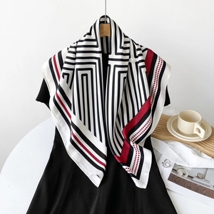 Close-up of lightweight silk scarf featuring black white stripes and red polka dot border