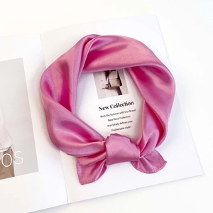 Close-up of bright magenta satin square scarf draped elegantly on a white magazine background