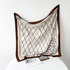 Detailed view of square silk scarf with brown lattice pattern and camellia floral design