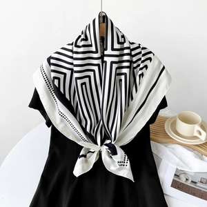 Detail of elegant black and white striped 90cm square silk scarf knotted on a chic outfit