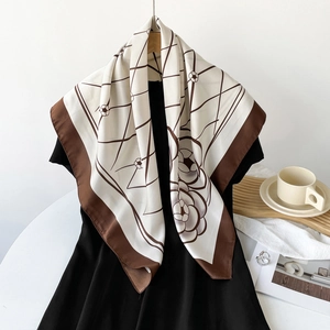 Elegant silk-like square scarf with floral pattern and dark brown border draped on dress