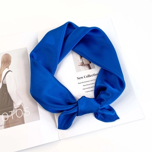 Close-up of bright blue silk scarf tied in a knot on a white background with a magazine