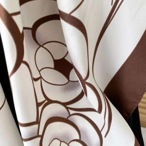 Elegant silk scarf featuring brown camellia patterns on a white satin finish fabric