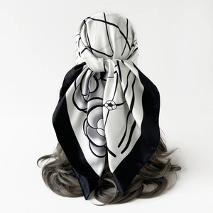 Detailed view of elegant white square scarf with black floral patterns and border