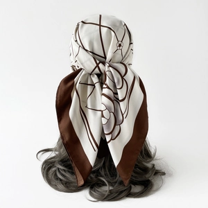 Detail of silk-feel scarf with camellia floral patterns worn as a chic headpiece
