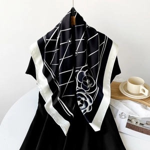 Detail of checkered silk scarf with rose patterns draped over a black dress for tea time