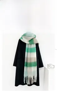 Close-up of thick mohair scarf featuring green and grey plaid pattern with heavy tassels