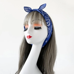 Detail of blue cotton paisley bandana headband with a rabbit ear bow on a display model