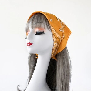 Detail view of yellow paisley bandana on a model head showing fabric texture and patterns