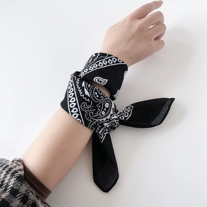 Close-up of black and white paisley bandana worn as a stylish wrist accessory on white background