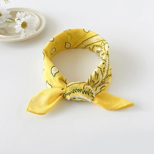 Detail of a knotted yellow cotton bandana with classic paisley patterns and floral decor
