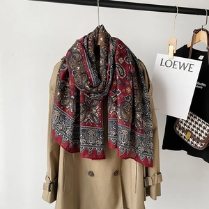 Detail of burgundy Paisley cotton linen scarf styled with a classic beige trench coat