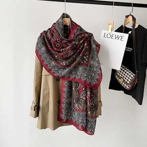 Detail of red paisley cotton linen scarf draped over a trench coat for styling