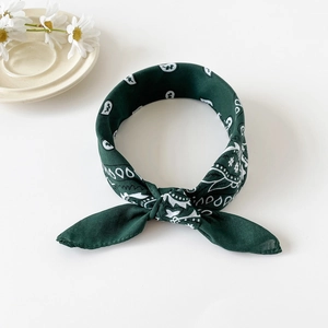 Close-up of dark green paisley bandana tied in a headband style with daisy decor