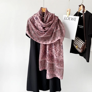 Detail of pink cotton linen scarf with purple paisley print hanging on a wooden hanger