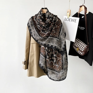 Detail showing paisley pattern on lightweight black linen scarf draped over a khaki trench coat