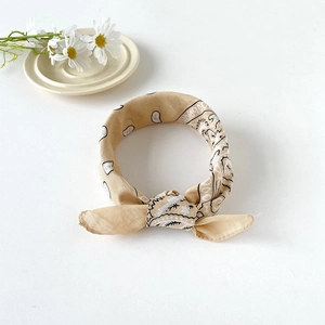 Detail of a beige paisley cotton bandana with a decorative bow knot for styling