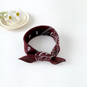 Close-up of deep burgundy paisley bandana with white floral pattern on a clean background