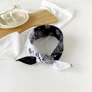 Detail of a black and white paisley bandana tied in a knot on a white rustic wooden tray