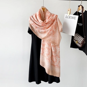 Detail of beige cotton-linen scarf with orange circular pattern draped on a hanger