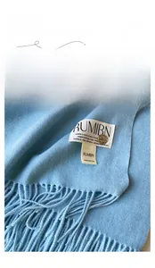 Détail de l'écharpe en maille bleu clair montrant la texture et le logo métallique
