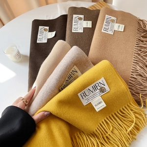 Détail de foulards au toucher cachemire avec longues franges et étiquettes dorées