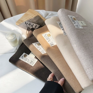 Détail d'écharpes en imitation cachemire aux tons terre avec emblème doré et étiquette de marque