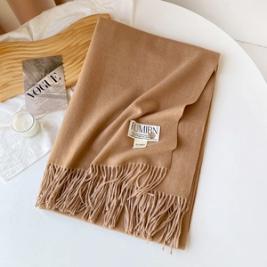 Détail d'une écharpe en cachemire camel montrant la texture fine et les franges