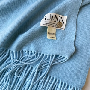 Gros plan sur écharpe bleu clair toucher cachemire avec tissage sergé, franges et logo doré