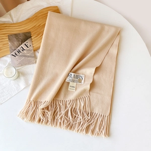 Détail d'une écharpe beige au toucher cachemire avec franges et étiquette de marque