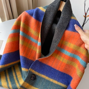 Detaillierte Makroansicht von bunt gestreiftem Strickponcho mit großem Knopf und Revers