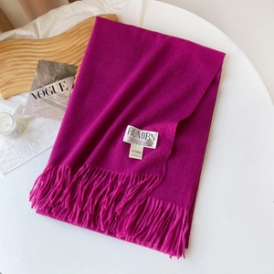 Détail d'une écharpe aspect cachemire rose rouge avec franges et étiquette tissée