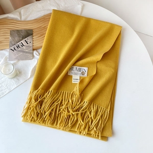 Détail d'une écharpe à franges jaune moutarde montrant la texture du sergé et l'étiquette