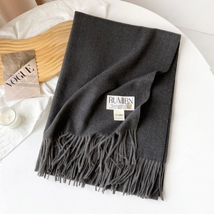 Détail d'une écharpe gris foncé en faux cachemire avec franges et logo en métal