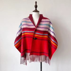 Detail eines roten Plaid-Schals mit bunten Streifen, schwarzem Knopf und Fransensaum
