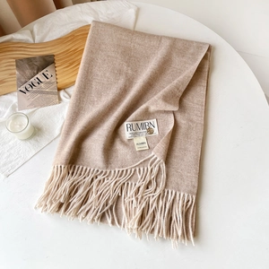Détail d'un châle en cachemire camel clair avec de longues franges et étiquette premium