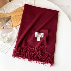 Détail de l'écharpe pashmina bordeaux avec franges épaisses et étiquette sur fond blanc