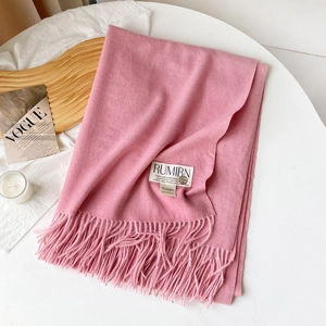 Gros plan sur l'écharpe rose aspect cachemire avec détails de franges et logo en métal