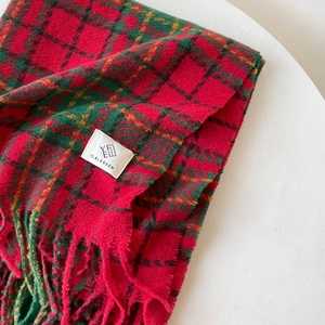Detail of red and green plaid scarf with soft bouclé texture and fine fringe edges