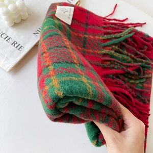 Detailed close-up of thick red and green plaid scarf with soft bouclé texture and long tassels