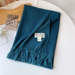 Détail de l'écharpe bleu canard effet cachemire avec emblème doré, étiquette et franges