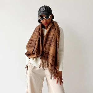Close-up of brown plaid scarf featuring decorative long fringe and thick wool texture