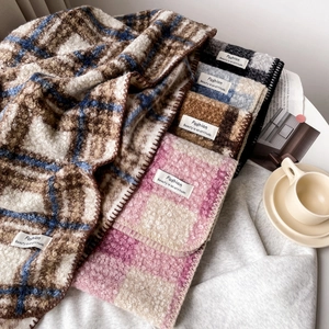 Nahaufnahme der weichen Plaid-Schal-Textur mit weißem Modeetikett und Fransen-Details